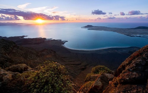 View from steep cliffs to sea and coast with sun stars, Mirador del Porrito viewpoint at sunset,