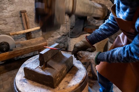 A dedicated elderly blacksmith in Salzburg, Austria, forges iron in his workshop, preserving