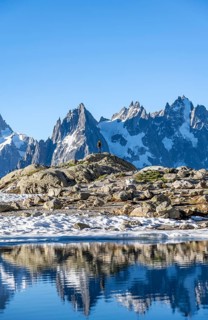 Young man in front of impressive mountain landscape in morning light, reflection in the Lac Blanc