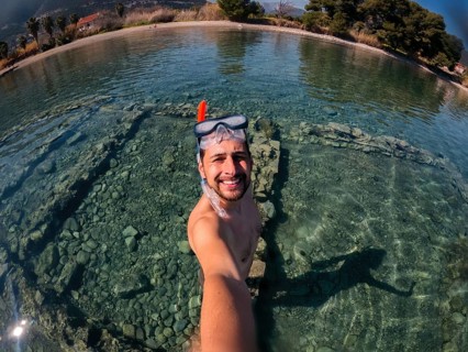 A snorkeler captures a selfie in the crystal-clear waters of Greece. The serene setting highlights