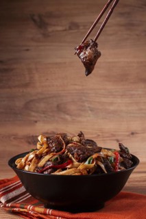 Udon noodles with beef in Mongolian style, with green onions and vegetables, served in a black