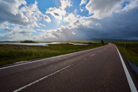 An expansive road leads along picturesque lakes under vivid and dramatic skies, Rannoch Moor,