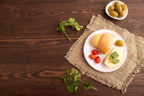 Smoked Mozzarella cheese, with tomatoes and olives on brown wooden background and linen textile,