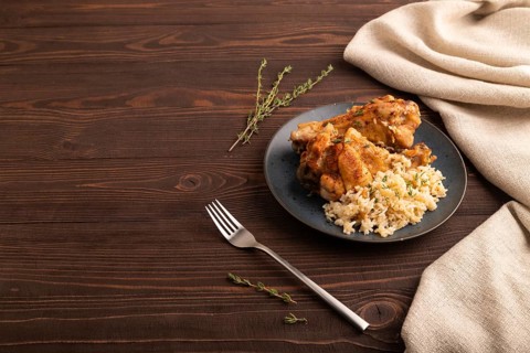 Fried Turkey Wing with spices and thyme on plate on brown wooden background and linen textile. side