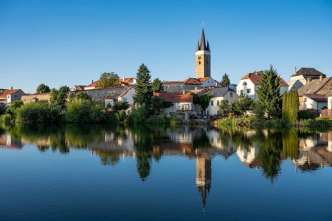 A wide panoramic view of the historic town of Telc with its colorful buildings and church towers