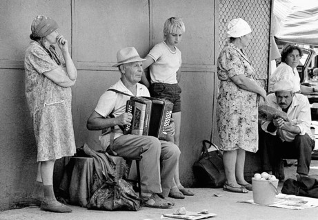 With an accordion, a family man plays folk songs at a vegetable market in Alma Ata, his son is