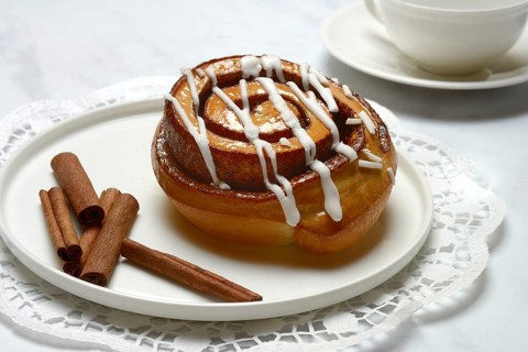 Cinnamon roll on plate and cinnamon sticks