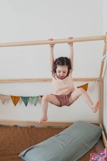 A joyful young girl hangs and plays indoors, showcasing her energetic spirit. The room is colorful