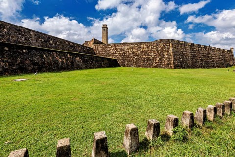 Stone walls of an old fortress with significant green space in the foreground, The fortress of