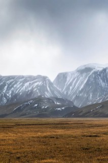 Expansive view of Iceland's highlands showcasing majestic, snow-capped mountains under a moody sky,
