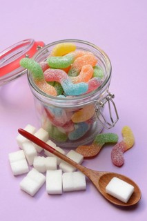 Lots of colorful jelly sweets in glass containers and sugar cubes, sugar consumption