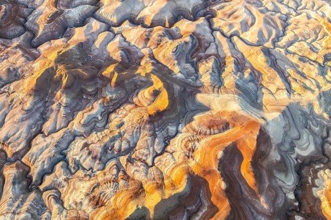 Aerial view showcases vibrant bentonite formations in Utah. The swirling patterns and rich colors