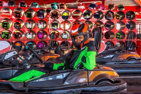 Young woman smiling and giving a fist pump in a go kart, ready for a fun racing experience at an