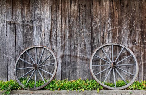 Two wagon wheels lean against a barn wall, Münsterland, North Rhine-Westphalia, Germany