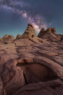 Stunning view of the Milky Way stretching across a starry night sky, above rugged, rocky desert