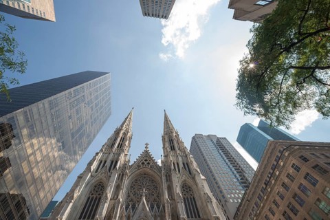A striking upward view capturing the iconic St. Patrick's Cathedral flanked by towering modern