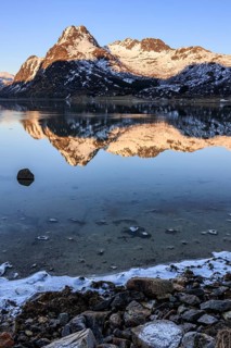 Fjord with steep snowy mountains, evening light, reflection, Flakstadoya, Lofoten, Norway