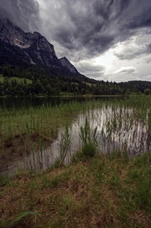 View of a lake with reeds and dramatic clouds over the mountains, Mittenwald, Bavaria, Germany