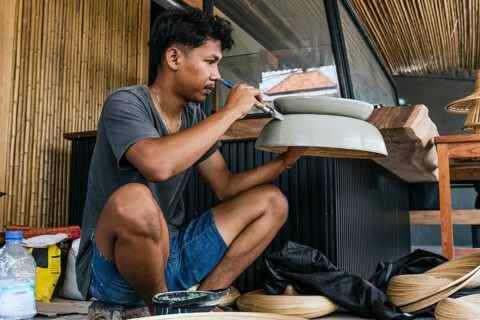 A Balinese artist meticulously paints a traditional sculpture, showcasing intricate craftsmanship.