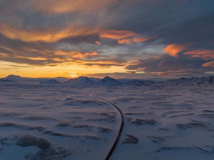 Stunning winter sunset over Iceland's snow-covered expanse, featuring dramatic skies and a winding