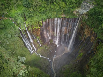 An aerial shot captures the stunning Tumpak Sewu Waterfall in full glory, showcasing multiple