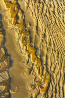 Aerial view of wind sculpted patterns in golden sandy terrain. Natural textures create abstract