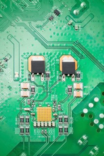 Detailed close up of a green circuit board showcasing chips electronic components and pathways.