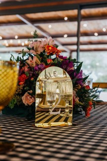 Close-up of a vibrant floral centerpiece with a golden mirror table number 2, surrounded by crystal