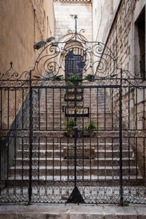 Wrought iron Tor tor, behind it stone flower pots on a staircase to a church in Figueras, Spain