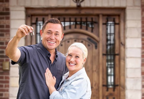 Young Couple In Front of Front Door of New House Holding Keys