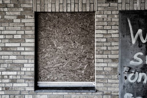 Old building with brick walls and a window covered with OSB panels