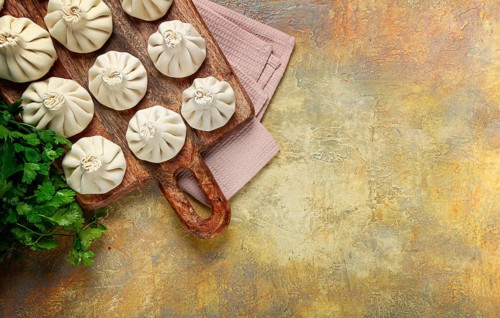 Freshly frozen raw khinkali, on a wooden chopping board, top view, Georgian cuisine, no people