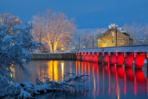 Illuminated Moulin Neuf water flow control dam and walkway over Des Mille-Iles river plus New Mill