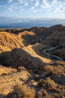 Canyon runs through a landscape of eroded hills at sunrise, Badlands, Issyk Kul Lake in the