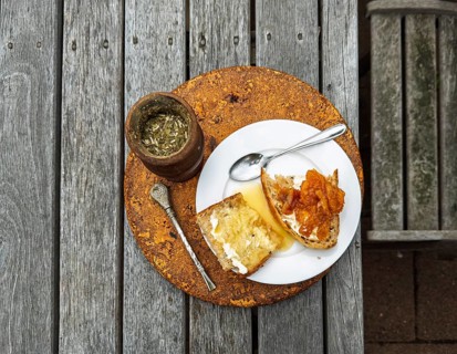 A rustic breakfast scene features slices of toast topped, accompanied by a cup of herbal tea. The