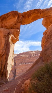 Captivating natural stone arch in the Wadi Rum desert of Jordan, set against a clear blue sky,