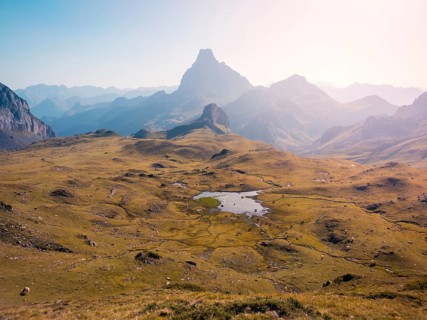 Scenic view of a tranquil mountain landscape with a prominent peak and expansive green valley,