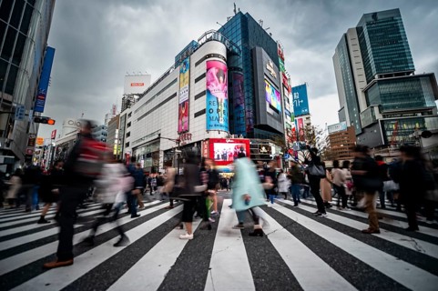 Crowd crossing zebra crossing on a large intersection, motion blur, back modern houses with