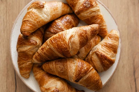 A plate of golden brown, flaky homemade croissants arranged artfully. This rustic presentation