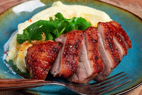 Roast duck breast, sliced with mashed potatoes, on a plate, close-up, no people