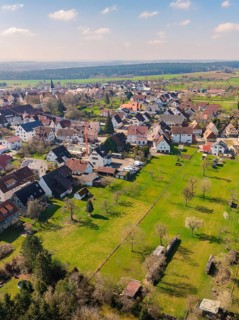 Village surrounded by large green spaces and scattered trees that emphasise the rural ambience,