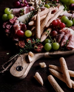 An enticing charcuterie board filled with a variety of snacks, including breadsticks, cured meats,