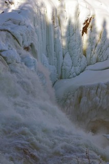 Waterfall partly frozen, with ice structures and shadows on the snow, winter, Sweden's highest