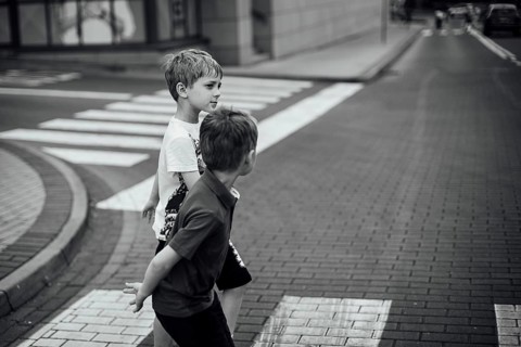 Two boys walk the pedestrian crossing on the street