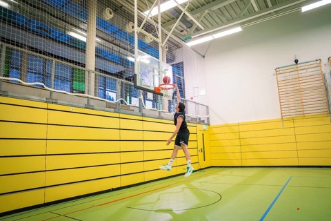 A basketball player throws the ball in a yellow gym, basketball TSV Calw, Germany