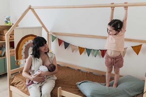 A joyous young family in a cozy nursery setting, where a mother lovingly holds her newborn baby