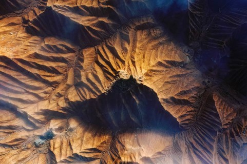 Aerial view showcasing a rugged desert landscape with intricate patterns and deep shadows Sunlight
