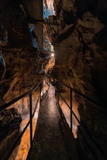 Narrow path through a cave, illuminated, surrounded by rocks and an adventurous atmosphere, Beatus