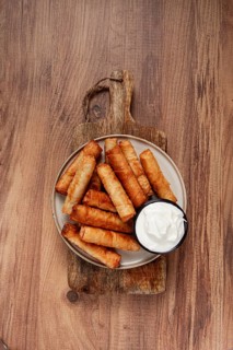 Fried spring rolls with cheese, on a wooden background, with cream sauce, no people