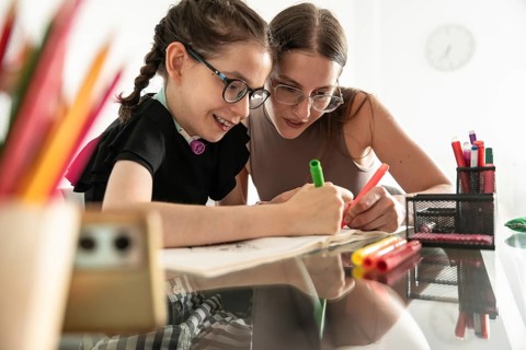 A heartfelt image of a sister supporting a disabled girl with a tracheostomy during a creative
